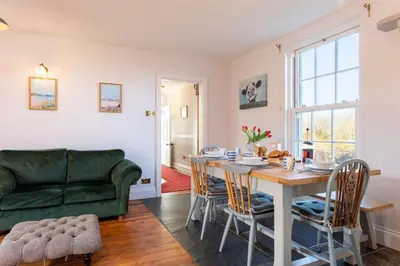 a living room with a table and a green couch at Millook View Farmhouse in Bude