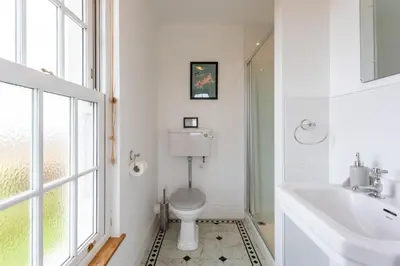 a white bathroom with a toilet and a sink at Millook View Farmhouse in Bude