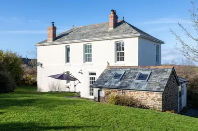 a large white house with a grass yard at Millook View Farmhouse in Bude