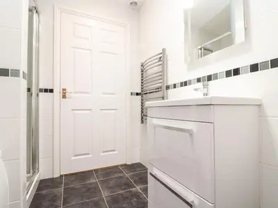a white bathroom with a sink and a white door at Gweal in Truro