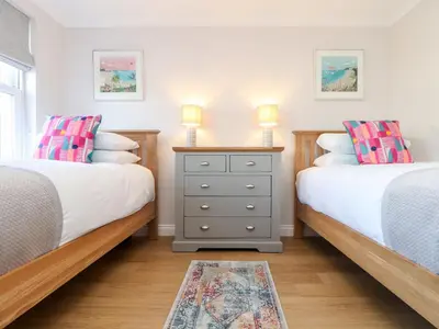 a bedroom with two beds and a dresser with two lamps at Gweal in Truro