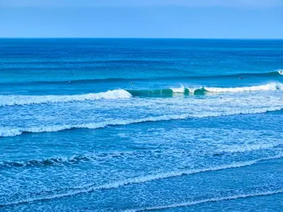 a group of surfers riding waves in the ocean at Tolcarne - Perranporth Cornwall in Perranporth