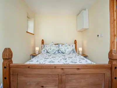 a bedroom with a wooden bed with pillows at Trelawney Cottage in Charlestown
