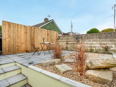 a patio with a fence and a table and some rocks at Trelawney Cottage in Charlestown