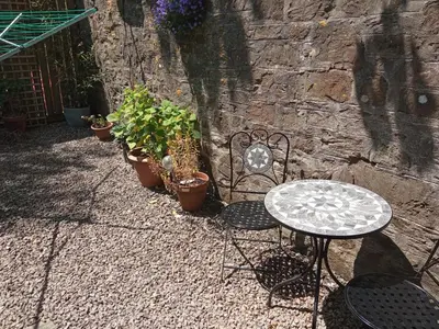 a table and chairs sitting next to a stone wall at Cozy Courtyard Apt Explore & Relax Free Parking in Bodmin