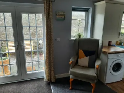 a living room with a chair and a washing machine at Cozy Courtyard Apt Explore & Relax Free Parking in Bodmin