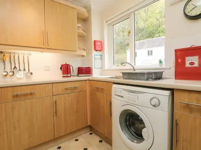 a kitchen with a washer and dryer in it at Mulberry Cottage in Falmouth
