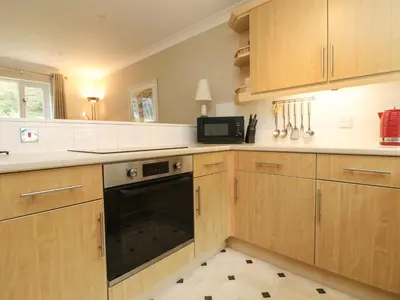 a kitchen with wooden cabinets and a black oven at Mulberry Cottage in Falmouth