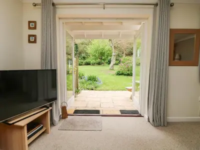 a living room with a television and a door to a yard at Mulberry Cottage in Falmouth