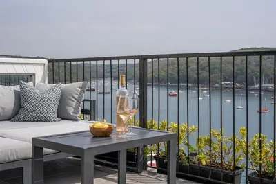 a table with a wine glass and a bottle on a balcony at Marners Rock No 3 in Fowey