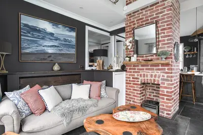 a living room with a couch and a brick fireplace at Marners Rock No 2 in Fowey