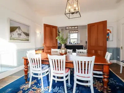 a dining room with a wooden table and chairs at Melvill House in Falmouth