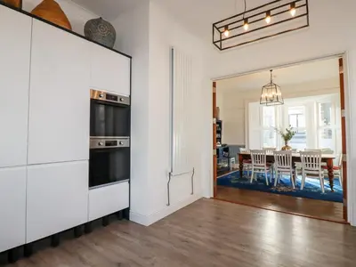 a kitchen with white cabinets and a dining room with a table at Melvill House in Falmouth