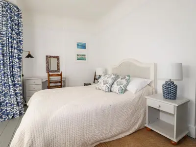 a bedroom with a white bed and a chair at Melvill House in Falmouth