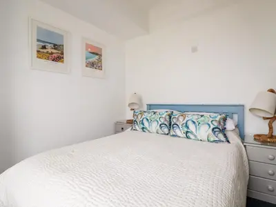 a white bedroom with a bed and two pictures on the wall at Melvill House in Falmouth