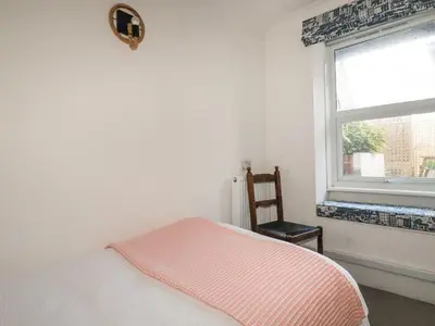a bedroom with a bed and a window and a chair at Melvill Lower Deck in Falmouth