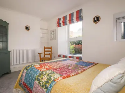a bedroom with a bed with a colorful quilt on it at Melvill Lower Deck in Falmouth