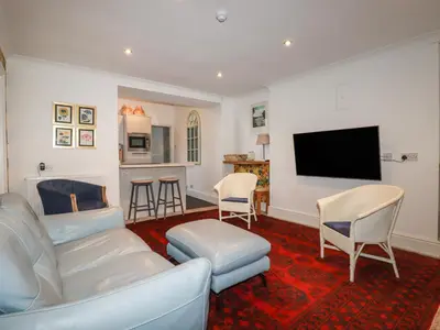 a living room with white furniture and a flat screen tv at Melvill Lower Deck in Falmouth