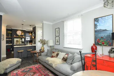 a living room with a couch and a kitchen at Marners Rock No 1 in Fowey