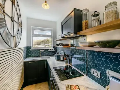 a kitchen with black cabinets and a blue tiled counter top at Oystercatcher - Mount Brioni in Downderry