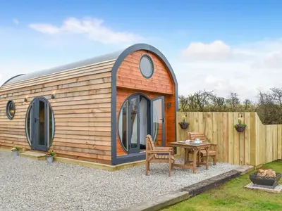 a tiny house with a table and a fence at Krowji Klys in Boscastle