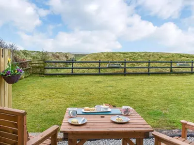 a wooden picnic table in a yard with a fence at Krowji Klys in Boscastle