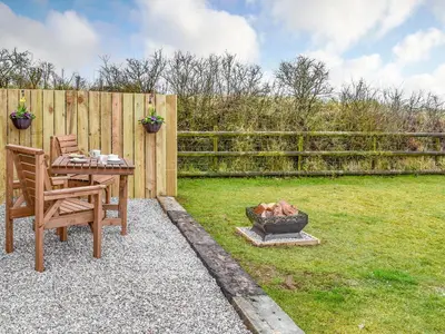a backyard with a table and a fire pit at Krowji Klys in Boscastle