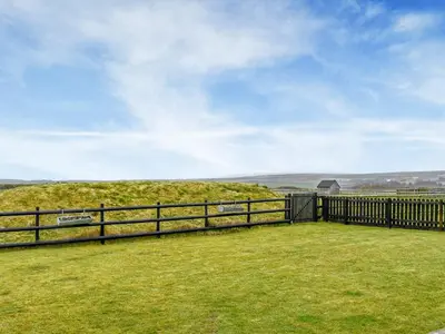 a wooden fence with a view of a hill at Krowji Klys in Boscastle