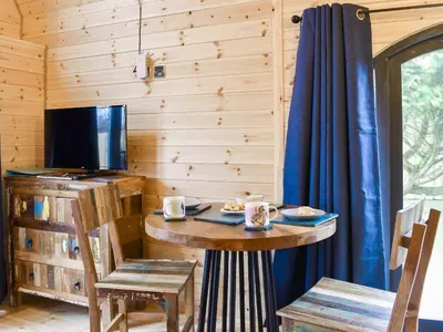 a dining room with a table and a tv in a cabin at Krowji Klys in Boscastle