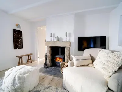a living room with a white couch and a fireplace at Bell Cottage in Saint Teath