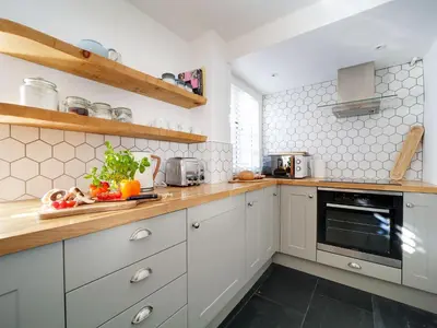 a kitchen with white cabinets and wooden counter tops at Bell Cottage in Saint Teath