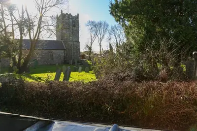 an old church with a tower in a cemetery at Bell Cottage in Saint Teath