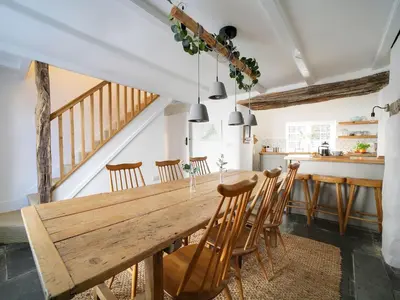 a kitchen and dining room with a wooden table and chairs at Bell Cottage in Saint Teath