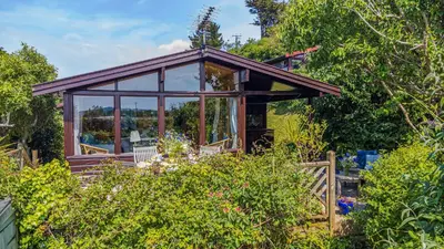 a small cottage with glass doors in a garden at Scandinavian Style Lodge in Rock in Wadebridge