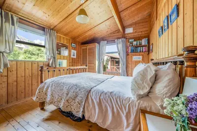a bedroom with a bed in a room with wooden walls at Scandinavian Style Lodge in Rock in Wadebridge