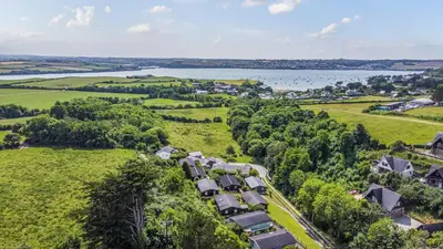 an aerial view of a village with trees and a lake at Scandinavian Style Lodge in Rock in Wadebridge