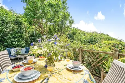 a dining table with a vase of flowers on it at Scandinavian Style Lodge in Rock in Wadebridge