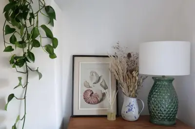 a table with a vase and a lamp and a picture at Wheelwright House in Bodmin