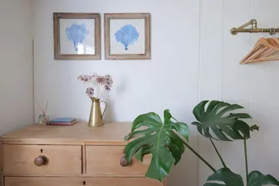 a wooden dresser with two pictures on the wall and a plant at Wheelwright House in Bodmin