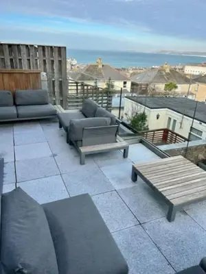 a patio with couches and tables on a balcony at George24 - spectacular, 5 minutes to the beach in Newquay