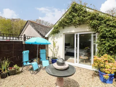 a patio with two chairs and an umbrella at Byghan Thornton in Redruth