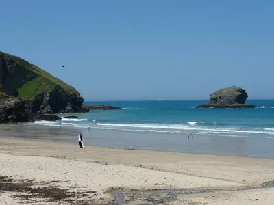 a beach with people walking on the sand and the ocean at Byghan Thornton in Redruth