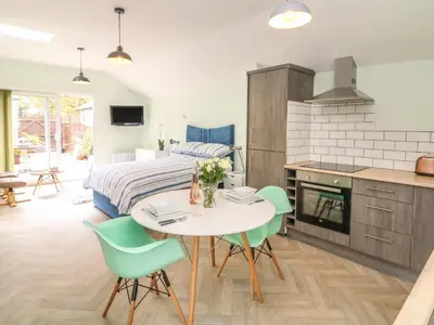 a kitchen and living room with a table and chairs at Byghan Thornton in Redruth