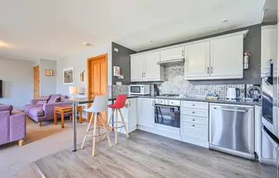 a kitchen with white cabinets and a table and chairs at 3 bed Lodge with EV point in Truro