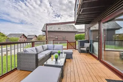a patio with a couch and a table on a deck at 3 bed Lodge with EV point in Truro