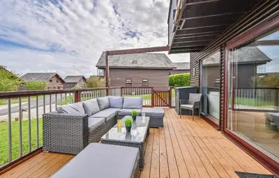 a patio with a couch and tables on a deck at 3 bed Lodge with EV point in Truro