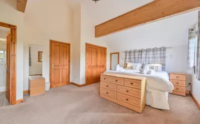 a bedroom with a large bed with a wooden dresser at 3 bed Lodge with EV point in Truro