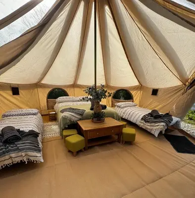 a tent with two beds and a table in a room at Polladras Holiday Park in Helston