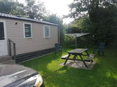 a picnic table and chairs in front of a house at Polladras Holiday Park in Helston