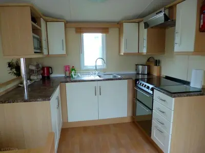 a kitchen with white cabinets and a sink at Polladras Holiday Park in Helston